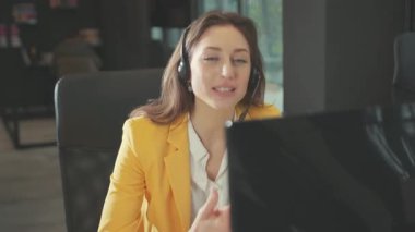 Kafkasyalı güzel genç kadın internet operatörünü destekliyor. Bilgisayar kameraları tarafından konuşuluyor. Video konferansında ofis çalışma alanındaki uzak dil öğrenme kursunda..