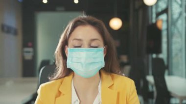 NEW YORK - 28 Mart 2020: Yüzü solunum maskesi çıkartan güzel girişimci genç kadın mutlu bir gülümseme ile gülümsüyor. Kadın portresi. Ofis çalışma alanı. Karantinanın sonu.