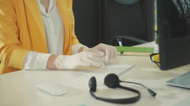 NEW YORK - 28 Mart 2020: Koruyucu tıbbi eldiven takan ofis çalışanı genç bayan şirkette temiz bilgisayar çalışma alanı üzerinde çalışırken maske takıyor. Sağlık, hijyen. Karantina 2020.