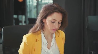 Şirketimizin ofisindeki masaüstü bilgisayarında çalışan şık takım elbiseli genç ve güzel girişimci kadın kameraya özgüvenli iş adamına bakıyor..