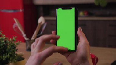 Tokio, Japonya - 7 Nisan 2018: Elli kadın, evde kahvaltıda mutfakta dikey yeşil ekranlı telefonu kullanırken, iş kadınlarının evlerinde sağlıklı, soyut, yavaş çekimde internet alışverişi yapıyor.