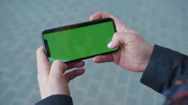 NEW YORK - 5 Nisan 2018: Meşgul sokak arkaplanı kaldırımında yatay yeşil sceen ile telefon tutan ellerini kapatarak internet teknolojisi kroma anahtar mesajı ile sörf sayfalarını kaydırıyor