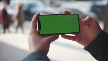 Lviv, Ukrayna - 19 Mayıs 2018: Şehir sokaklarının arka planında elinde yatay yeşil ekranlı bir telefonla el ele tutuşan kadınların görüntüsü.