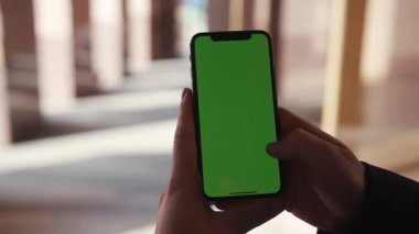 Lviv, Ukrayna - 19 Mayıs 2018: Şehir merkezinde, elinde yatay yeşil ekran arka plan günbatımı ile dokunmatik telefon kullanan kadın.