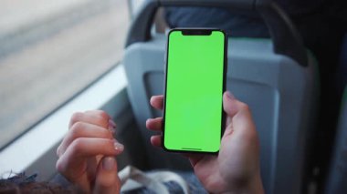 Lviv, Ukrayna - 19 Mayıs 2018: Ağır çekimde çalışan kadınlar cep telefonlarını dikey yeşil ekranda, tramvay anahtarı, akıllı telefon teknolojisi, cep telefonu, sokak mesajı görüntüleme ekranında tutuyorlar.
