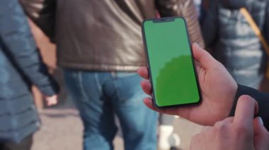 Lviv, Ukrayna - 19 Mayıs 2018: El ele tutuşan bir kadının cep telefonunu dikey yeşil ekran sokak insanlarının yürüdüğü krom anahtar görüntülü akıllı telefon teknolojili cep telefonu mesajı