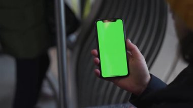 Lviv, Ukrayna - 19 Mayıs 2018: Kız, tramvay krom anahtar akıllı telefon teknolojisi cep telefonu teknolojisi ile dikey yeşil ekranlı cep telefonu ile cep telefonuna dokunarak el ele tutuşur