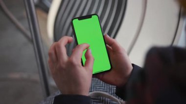 Lviv, Ukrayna - 19 Mayıs 2018: Eller, tramvay krom anahtar akıllı telefon teknolojisi ile dikey yeşil ekranlı bir cep telefonu ile temas halinde.