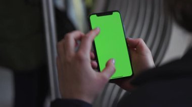 Lviv, Ukrayna - 19 Mayıs 2018: Genç kadın elleri, tramvay krom anahtar akıllı telefon teknolojisi cep telefonu sokak dokunma mesajı içeren dikey yeşil ekranlı bir cep telefonu kullanıyor