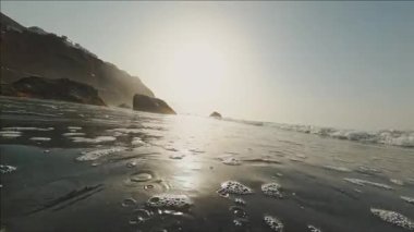 FPV 'deki vahşi deniz manzarası. Büyük dalgalar ve güneş ışığı sahnesiyle okyanus suyunda yüzmek. Gün batımında güzel deniz manzarası.