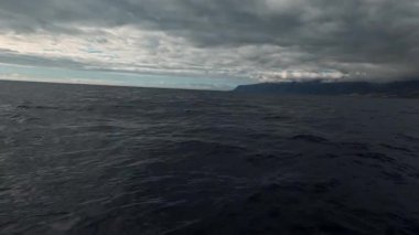 Fırtına sırasında sonsuz güzel okyanusta yüzmek. Harika denizin üzerinde harika bir kara bulut manzarası. Fırtınalı hava. Deniz aktiviteleri.