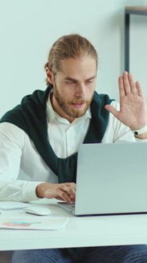 A man is sitting comfortably at a desk engaging with a laptop computer, deeply focused on his work or personal tasks on the device