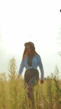 Tarz sahibi hasır şapkalı bir kadın, sakin bir günün tadını çıkarır. Resimli bir tarlada, sakin bir maceraya ya da açık araba bagajıyla pikniğe hazırlanır.