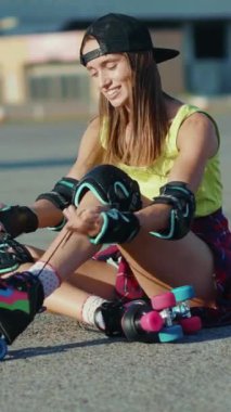 Bir kadın, hareketlerinin keyfini çıkarmadan önce patenlerini güvenli bir şekilde bağlarken yerde rahatça oturuyor.