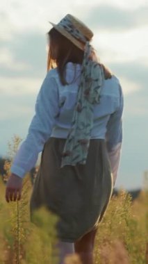 Bu videoda hasır şapkalı ve eşarplı bir kadın güneş bataryasında yürüyor, huzuru ve güzelliği somutlaştırıyor.