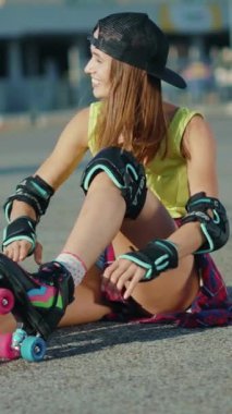 Neşeli bir kadın patenlerini takmak için oturur, onları kararlılıkla bağlar, paten kaymanın eğlencesi ve özgürlüğüne hazırdır.