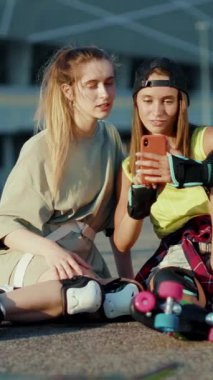 İki genç kadın cep telefonuna bakarken keyifli bir anı paylaşıyorlar. İfadeleri merak ve heyecanı, dostluğu ve modern bağlantıyı simgeliyor.