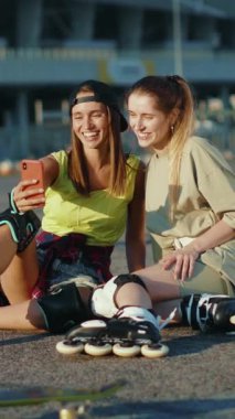 İki genç kadın açık havada güneşli bir günün tadını çıkarıyor. Cep telefonlarıyla selfie çekiyorlar. Arkadaşlıklarını ve maceraperest ruhlarını sergiliyorlar.