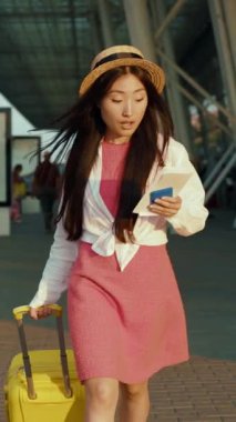 Şık yaz kıyafetleri içinde genç bir kadın bavuluyla güvenle yürüyor, maceralarının tadını çıkarıyor.