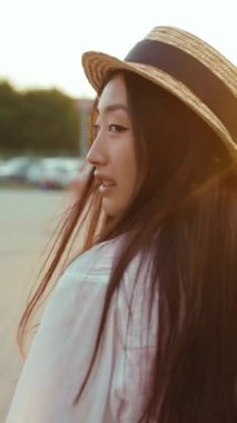 Güzel günbatımı titreşimlerine dalmış, uzun saçlı, saman şapkalı, dingin bir kadın sahnesi.