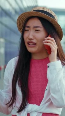 Moda kıyafetleri içinde neşeli genç bir kadın şehir dışında canlı bir telefon görüşmesi yapıyor.