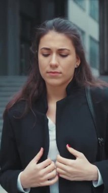 Siyah paltolu genç bir kadın şehir ortamında düşünceli görünüyor, modern moda sergiliyor..