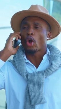 Şık bir adam, şık bir şapka ve açık havada şık bir eşarp giyerken bir telefon görüşmesi yapar.