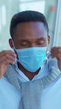 Modaya uygun genç bir adam, çarpıcı mavi bir maske ve şık bir kıyafet giyiyor, kendine güven ve cazibe yayıyor.