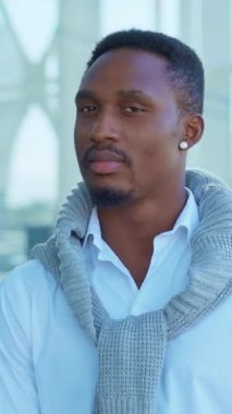 Şık bir adam, kendine güveni tam beyaz gömleğini şık gri bir süveterle şık bir şekilde sergiliyor, göz alıcı bir çekiciliği var.