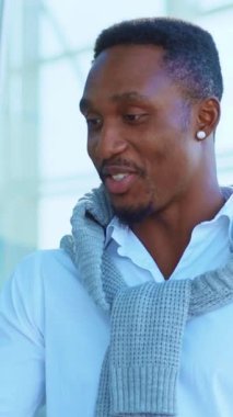 Şık giyinmiş neşeli bir adam, elinde akıllı bir telefon, canlı, modern bir yaşam tarzını simgeliyor.