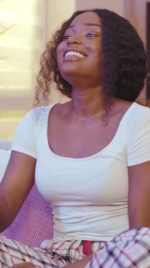 Neşeli, kıvırcık saçlı, sıradan giyinmiş, neşeli bir kadın. Keyifli bir kahkaha anı yaşıyor.