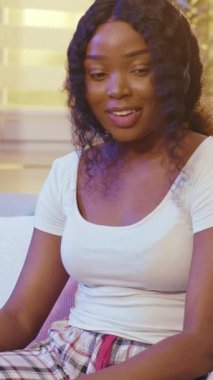 Şık kulaklık takan neşeli genç bir kadın aktif olarak canlı ve ilgi çekici bir sohbete katılıyor.