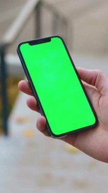 Bir el, medya oluşturma ve görüntüleme için mükemmel olan yeşil ekranı gösteren bir akıllı telefonu tutuyor.