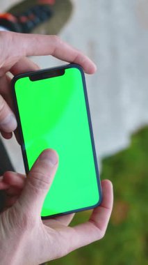 Parlak yeşil ekranlı akıllı telefonu tutan ellerin yakın çekimi, medya düzenleme ve yaratıcı projeler için mükemmel.