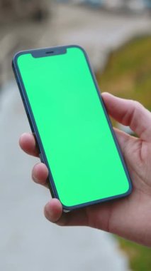 Bir kişi canlı yeşil ekranlı akıllı bir telefon tutar, uygulama demolarını veya dijital içeriği göstermek için idealdir