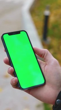 Elinde yeşil ekranlı akıllı telefon tutan bir kişi, uygulama tanıtımı ya da tanıtım amaçlı kullanılabilir..