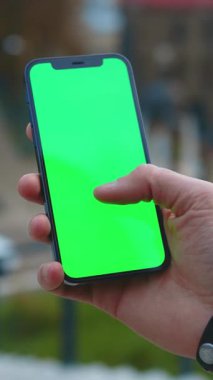 Bir el, medya üretimi ve reklamcılığı için ideal, canlı yeşil ekranlı bir akıllı telefonu tutuyor.