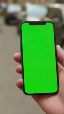 Elinde canlı yeşil ekranlı akıllı bir telefon tutan kişi dijital reklamlar ve sunumlar için mükemmel..