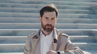 Akıllı saat kullanan çekici bir portre arka plandaki sokakta gülümseyen kameraya bakın. Kapatın. Yavaş çekim