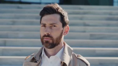 Ceketli yakışıklı bir portre arka merdivenlerde kameraya bakıyor. Şehir caddesinde güneş ışığı. Yavaş çekim