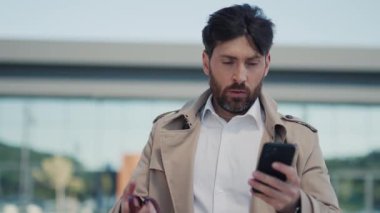 Yüzü asık bir iş adamı akıllı telefon kullanır saate bakar şehir caddesinde hayal kırıklığına uğramış hisseder. Şehir merkezine yakın bir yerde dur. Yavaş çekim