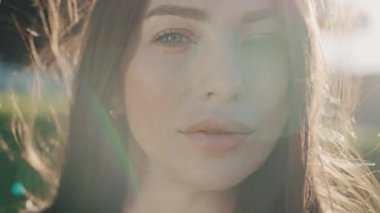 Gün batımında genç ve çekici bir kadın kameraya gülümsüyor. Rüzgârlı. Dışarıda dur ve rahatla. Yavaş çekim