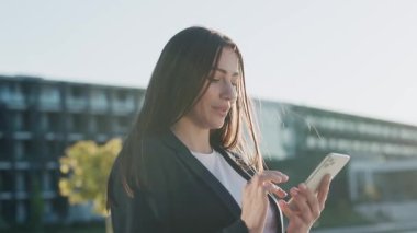 Şehir merkezinde gün ışığında telefonu kullanan çekici genç bir kadını kapat ve etrafına gülümse. Cep telefonu olan bir portre kızı. Yavaş çekim