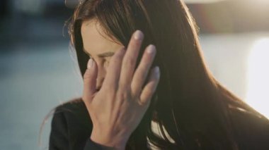 Kameraya bakıp gülümseyen çekici kadın gün ışığında şehir merkezinde mutlu hissediyor. Açık hava fotoğrafçısı kız. Rüzgârlı. Yavaş çekim