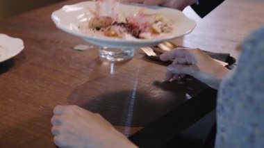 Restoranda bir bayan konuğa servis yapan garsonu kapatın. Yemek vakti. Yiyecekler. Lezzetli. Yavaş çekim