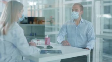 Tıbbi maskeli hasta, doktor kadınla konuşuyor. Göğüs röntgeninin klinikte muayene odasında sonuçlandığını açıklıyor. Pandemik koronavirüs tedavisi. Yavaş çekim