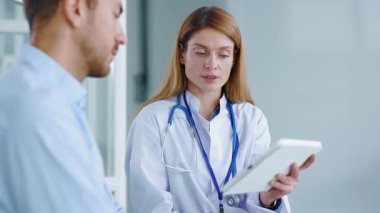 Gülümseyen doktor kadın muayene sırasında erkek hastayla konuşuyor. Hastanede. Yavaş çekim