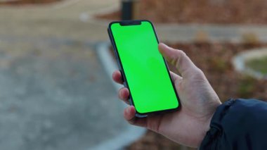 NEW YORK - 19 Aralık 2020: Kentteki dikey yeşil ekran arka plan aydınlatma yolu ile dokunmatik telefon kullanarak insan elini kapat. İnternet krom açık hava cep telefonu akıllı telefonları kayıyor. Yavaş çekim