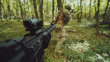 Askeri harekat sırasında ormandan geçerken silahla nişan alan askerin yakın çekim görüntüleri. Ormanda kamuflaj üniforması giyen bir grup donanımlı savaşçı. Açık havada. Saldırı ve savaş kavramı