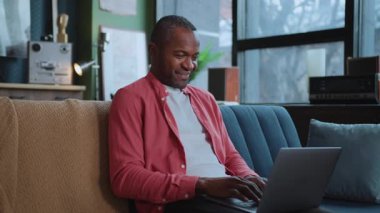 Gülümseyen blogcu takipçilerle sosyal medyada sohbet ederken ve klavyede klavye çalarken görüntüler. Gülümseyen yakışıklı Afro-Amerikan bir adamın portresi. İletişim. Kapalı